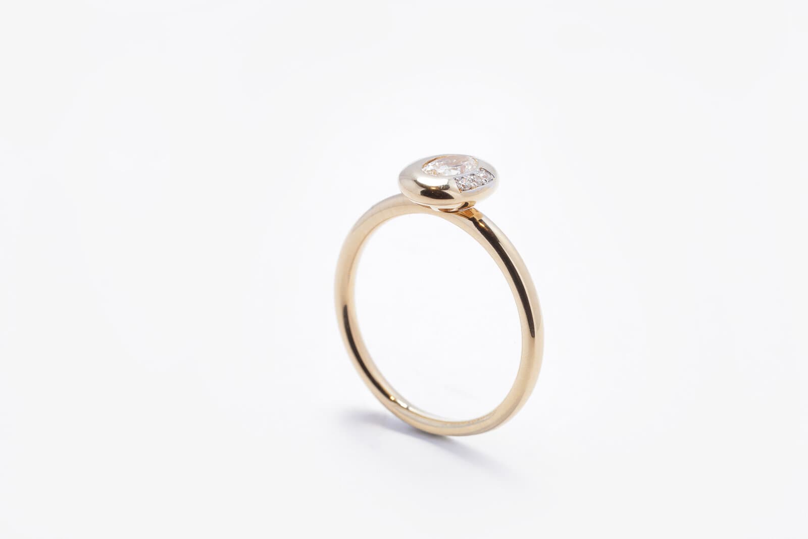 A sleek yellow gold ring featuring an oval center diamond